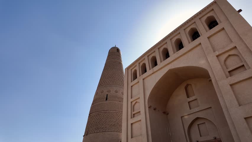 Turpan, China: Pan footage of the famous Emin Minaret next the the entrance of the Uyghur mosque that dates back from 1777 in the Turpan oasis in Xinjiang in China. Shot with front light sun. 