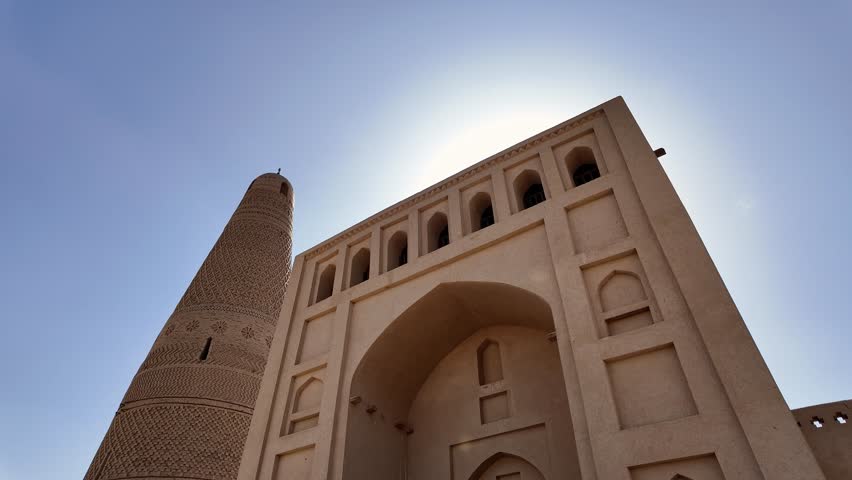 Turpan, China: Tilt down footage of the famous Emin Minaret next the the entrance of the Uyghur mosque that dates back from 1777 in the Turpan oasis in Xinjiang in China. Shot with front light sun. 