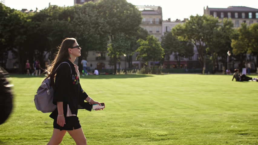 Romantic girl tourist walks through the park in Paris. Travel to the capital of France, beautiful city landscapes.
