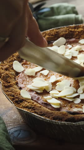  Vertical video. Cutting Pumpkin Pie Sprinkled with Almonds. Homemade cooking thanksgiving pie
