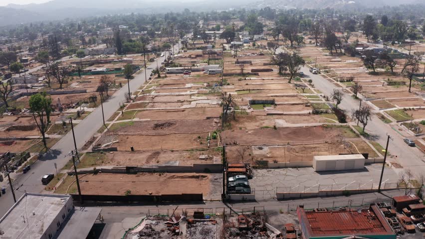 Aerial tilting-up shot flying over cleared residential lots in the aftermath of the Eaton Fire in Altadena, California. 4K