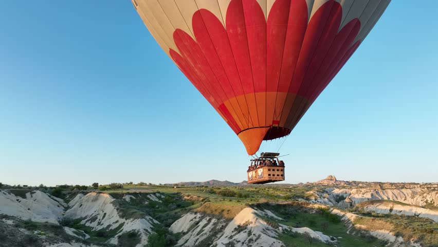 Aerial view of many colorful hot air balloons fly in the sky over a mountain valley at summer sunrise in Cappadocia, Turkey