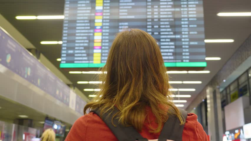 Discovering new journeys as a traveler explores bustling airport terminal with dynamic flight information boards