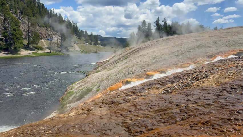 Scenic landscape view of a stream of boiling water from the Midway Geyser Basin in Yellowstone National Park entering the Firehole River