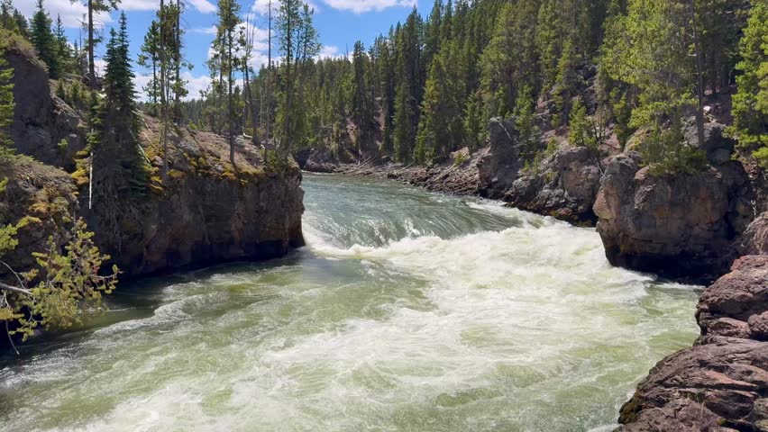 Scenic landscape view of water on the Yellowstone River dropping over the Upper Falls in Yellowstone National Park. Panning right to left.