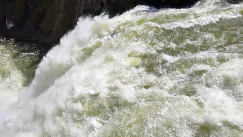 Close up view of the fast-flowing Yellowstone River dropping over the edge of the Upper Falls in Yellowstone National Park. 