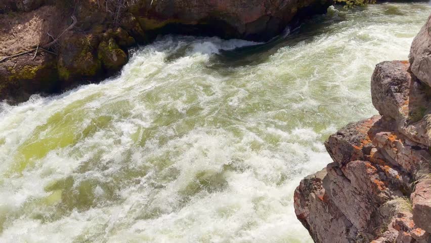 Scenic landscape view of water on the Yellowstone River dropping over the Upper Falls in Yellowstone National Park. Panning right to left.