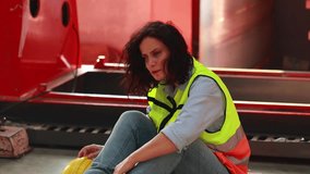 Unhappy lonely depressed and sad feeling. female blue-collar worker sitting in warehouse. caucasian woman professional engineer worker working at metal sheet profiling factory. metal roof tile roll - Powered by Shutterstock - Get 15% off with code: PIKWIZARD15