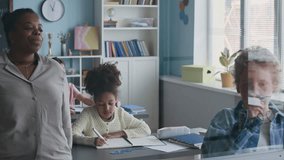 Young Caucasian student in plaid shirt standing by transparent board near Black female teacher and solving Math problems as his diverse classmates observing from their desks - Powered by Shutterstock - Get 15% off with code: PIKWIZARD15