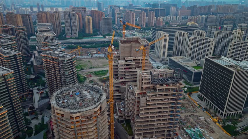 Construction progress of a skyscraper in a bustling urban area during sunset. China, Hangzhou.
