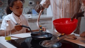 African American father man hand frying pancakes together with daughter. Family daily routine, common habits, healthy food cooking for dinner, dad and child active lifestyle - Powered by Shutterstock - Get 15% off with code: PIKWIZARD15