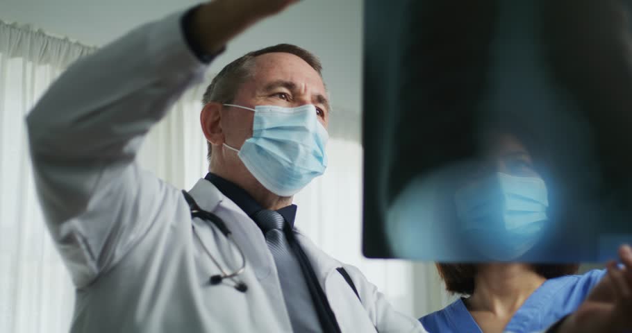 A medical professional analyzes a chest X-ray showing rib structure, highlighting specific areas with blue arrows for diagnosis or teaching.