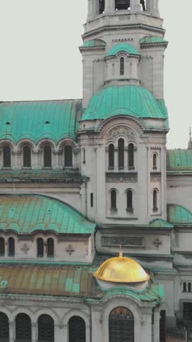 Aerial view of the Alexander Nevsky Cathedral located in Sofia, Bulgaria, highlighting the characteristic green oxidized copper of its roofs. Vertical Video, Rising Shot