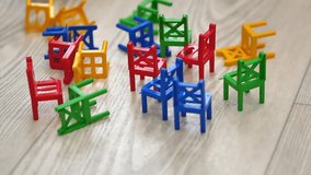 The board game chairs. Colorful plastic chairs are on the floor, and in the background a child is assembling a tower. The concept of a board game and children's leisure. - Powered by Shutterstock - Get 15% off with code: PIKWIZARD15