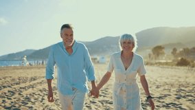Retired couple walking hand in hand along sandy shoreline, radiating joy and love while enjoying peaceful sunset moments during seaside vacation together - Powered by Shutterstock - Get 15% off with code: PIKWIZARD15