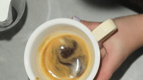 Professional barista shakes cup of coffee pouring milk from mug into drink. Woman shows part of process of making Americano above table - Powered by Shutterstock - Get 15% off with code: PIKWIZARD15