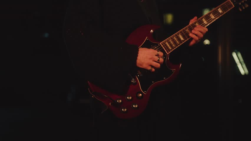 close-up fingers on guitar strings. man playing guitar on stage musician singer during performance. person performs in front audience sings. atmospheric creative mood inspiration light soffits blurred