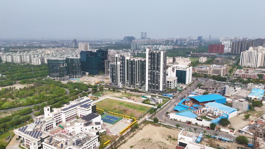 Aerial drone shot of commercial complexes and metro lines in Noida from the sky.