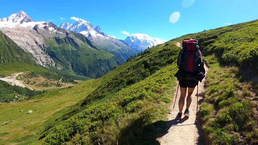 sstkTravel. Hiker in the ALPS mountains - following the TMB (Tour du Mont Blanc) trail. Scenic background of mountains with snow peaks and glacier.