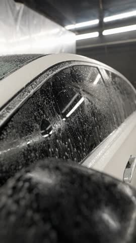 Car being washed, covered in soap suds and water drops. Car wash concept.