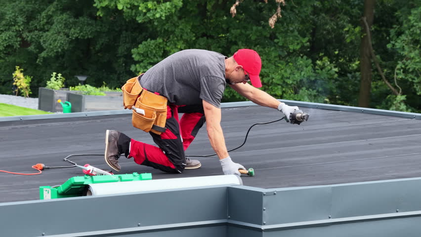 A contractor is focused on installing new EPDM Vinyl roofing material on a flat roof in a suburban neighborhood, ensuring durability and protection for the home.