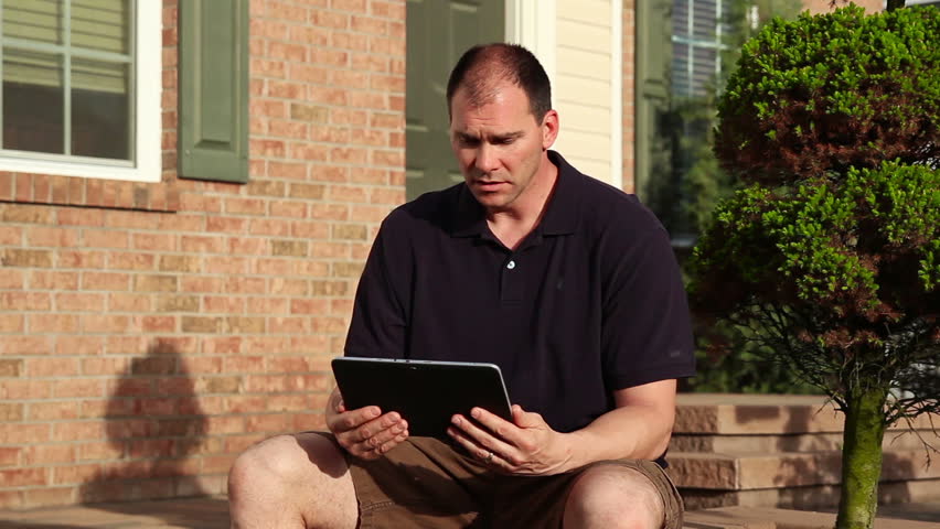 A man video chats on his tablet PC outside his home. Screen image customizable