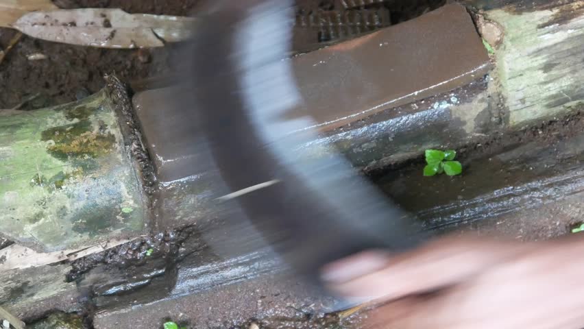a man's hand sharpening a machete on a sharpening stone