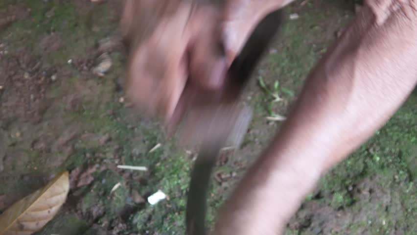 a man's hand sharpening a machete on a sharpening stone