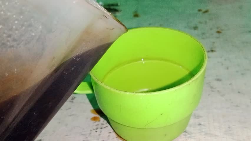 pouring coffee into a green plastic cup.