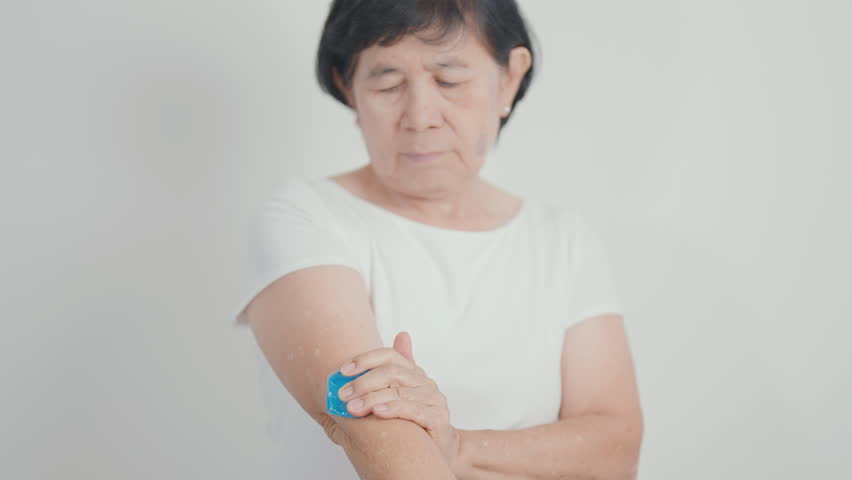 Elderly Woman having elbow ache and Edema with Cold Gel pack  for concepts of Tennis Elbow, muscle pain and Sprain, lateral epicondylitis, Bursitis, injury, Senior Health care and medical 