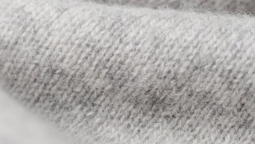 Macro shot reveals tactile fibers and knit pattern of grey folded blanket