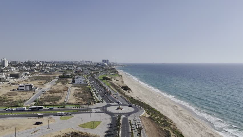 4K drone footage of Israel’s coastal highway along Ashkelon Beach – showcasing the scenic road by the Mediterranean Sea, a modern beachfront promenade, and calm ocean waves. 