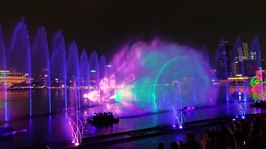 Marina Bay dancing fountain lights show at night in front of Singapore skyline. 4K video footage