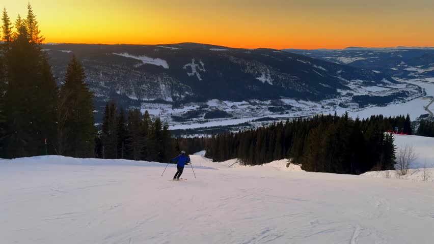Vibrant artic sunset golden hour telemark downhill skier skiing Hafjell Alpine ski resort Øyer mountain Norway Norge Olympic torch man Lillehammer clear skies groomed trail runs icy packed follow