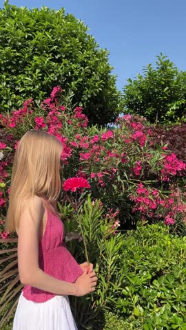 A beautiful young girl with one pink flower in the park