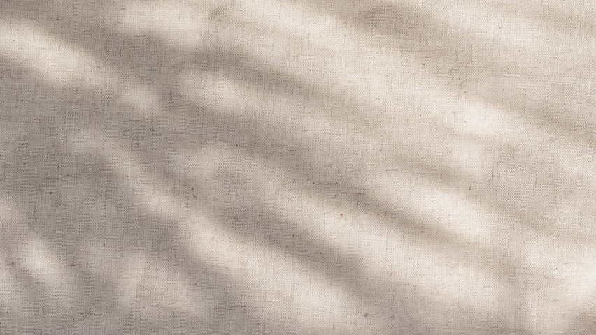 Camera pushes into linen texture as strong rays reveal warm woven detail