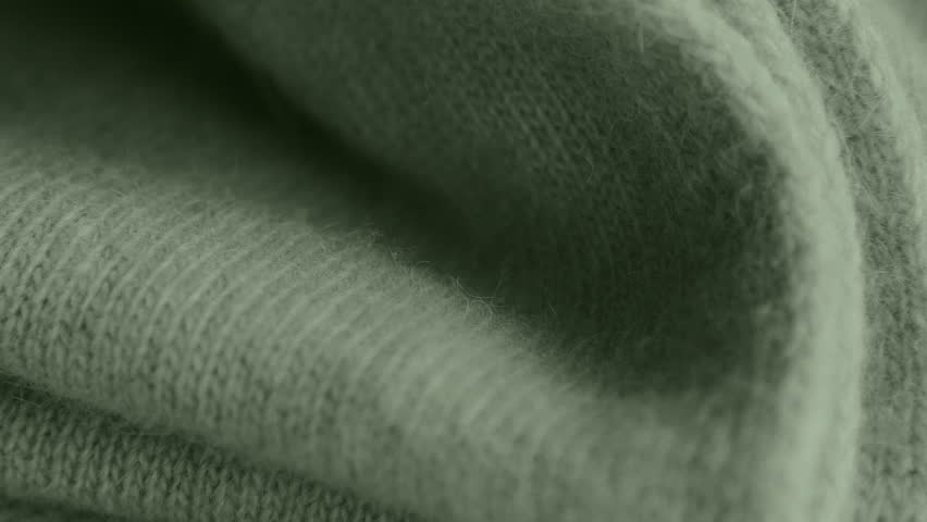 Camera pushes into green wool folds, revealing tactile weave and cozy fibers