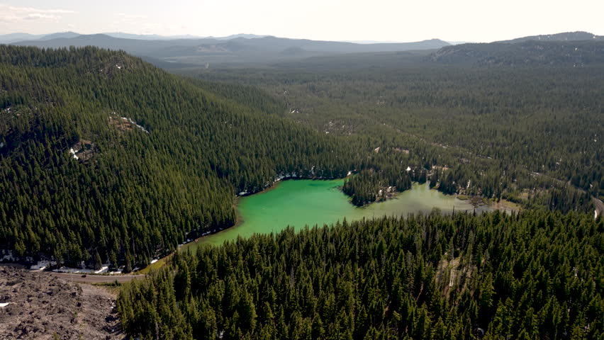 Devils Lake, Oregon. Drone orbit over lava fields with lake and forest in distance.