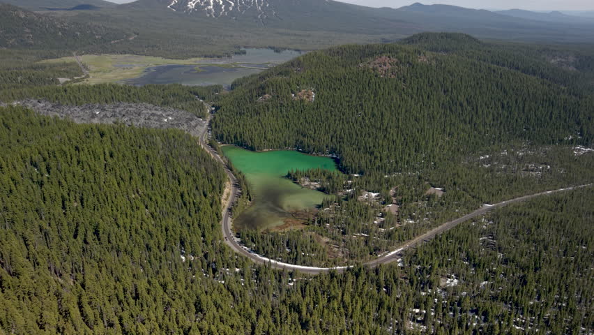 Wide panoramic drone shot of Mount Bachelor, Sparks Lake, Devils Lake and winding Cascade Lakes Highway.