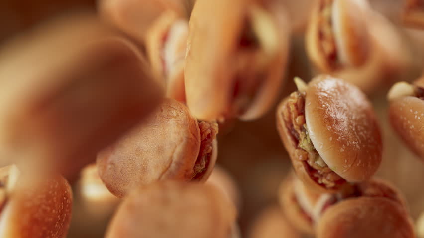 Animation of a group of burgers. Many burgers slowly rotate in the background in space. Horizontal composition. Defocus. Close-up.