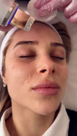 Facial cleansing with ultrasound scrubber. Woman receiving ultrasound facial peeling and cleansing. Cosmetology and face skin care. Facial treatment