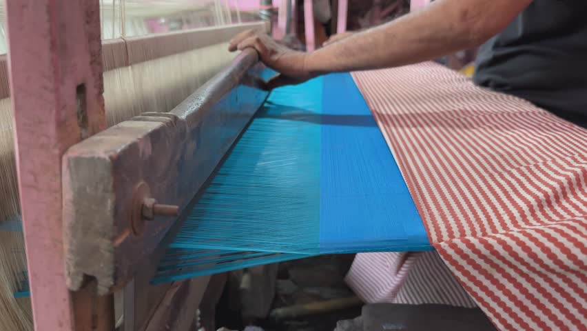 closeup shot of indian handloom operator's hand using the tana bana a small device used by indian traditional handloom textile operator