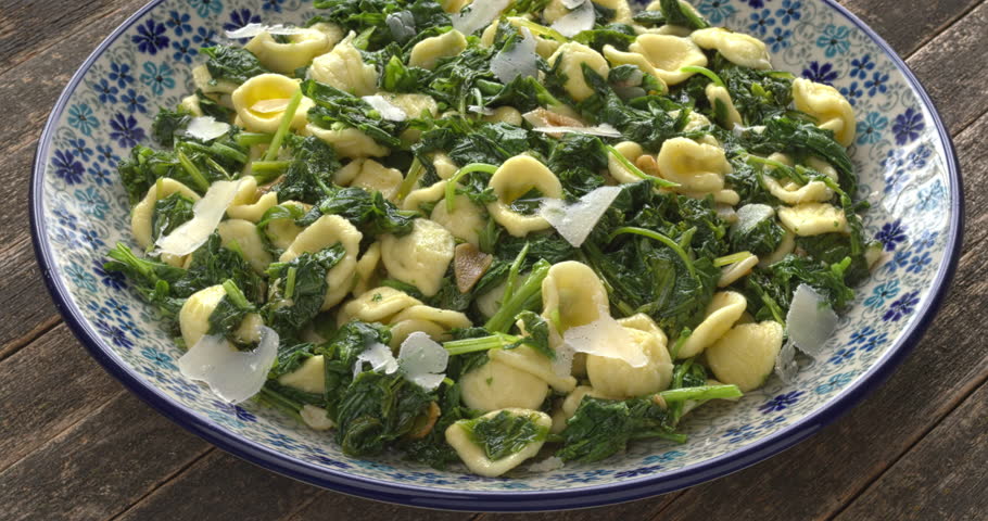 Orecchiette pasta with broccoli rabe (rapini) on a plate. South Italian dish. Rapini is a rich source of vitamin K. Table spin.
