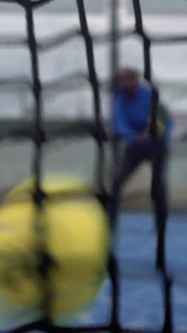 Slowmotion through grid view of paddle tennis man playing on blue court outdoors. One caucasian padle player sportman hitting the ball. Racquet sport game Concept.