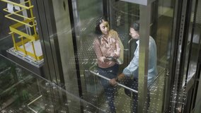 Descending elevator car carrying business colleagues analyzing data with holographic binary overlay. Futuristic, corporate, innovation, technology, networking, communication, professional - Powered by Shutterstock - Get 15% off with code: PIKWIZARD15