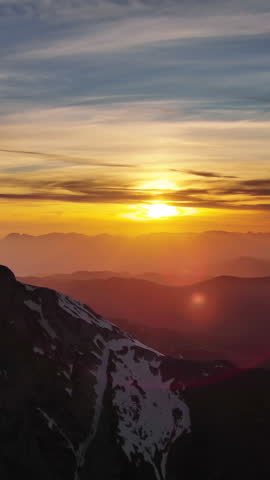 Aerial view of amazing rocky mountains in snow and sunset sun. Vertical video 4k