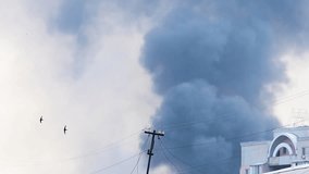 Thick column of dark smoke rises over urban area - Powered by Shutterstock - Get 15% off with code: PIKWIZARD15