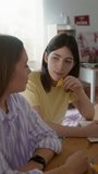 Vertical shot of two young girls studying together and chatting while eating snacks in dorm room - Powered by Shutterstock - Get 15% off with code: PIKWIZARD15