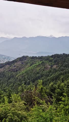 Panoramic view from a hill station. Small houses nestle by a serene lake below, an expansive, breathtaking town vista.
