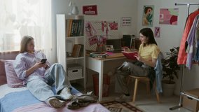 Wide angle shot two teenage girls as students interacting in colorful dorm room and chatting while studying for exams - Powered by Shutterstock - Get 15% off with code: PIKWIZARD15